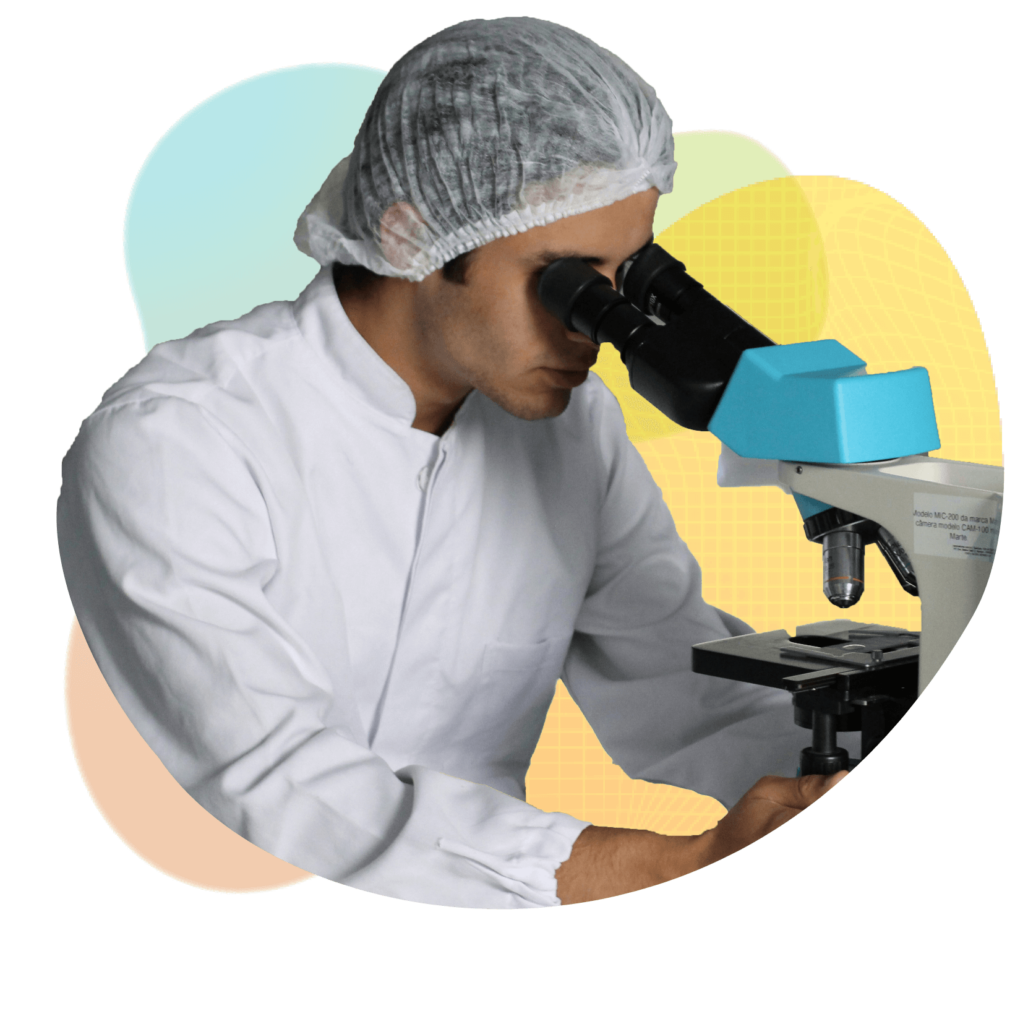 Man wearing lab coat looking down microscope